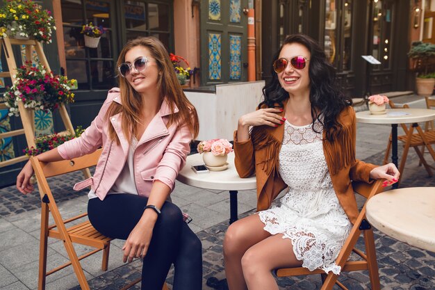 Twee jonge stijlvolle vrouwen zitten in café