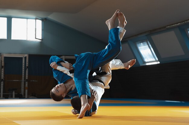 Twee jonge vechters in kimono training martial arts in de sportschool