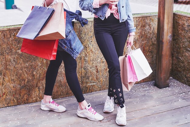 Twee jonge vrouw met boodschappentassen tijdens het wandelen in de straat na een bezoek aan de winkels.