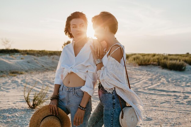 Twee jonge vrouwen die plezier hebben op het zonsondergangstrand