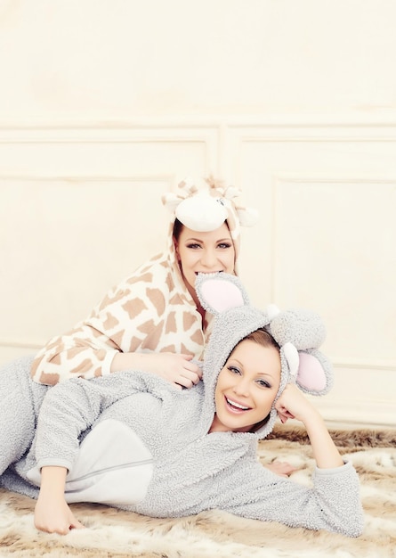 Twee jonge vrouwen in een pyjama die plezier hebben.