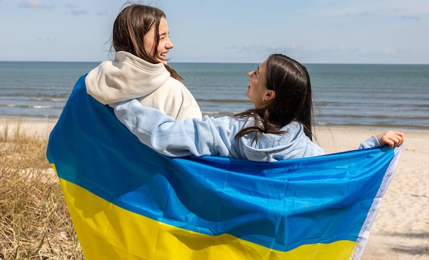 Gratis foto twee jonge vrouwen met de vlag van oekraïne op de achtergrond van de zee