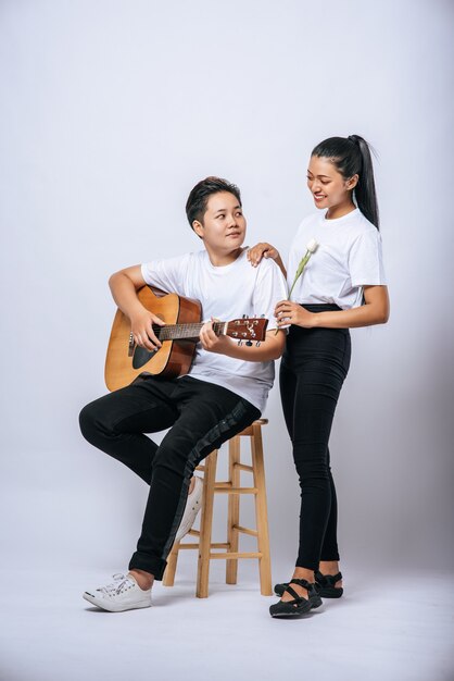 Twee jonge vrouwen zaten op een stoel en speelden gitaar.