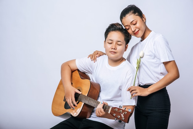 Twee jonge vrouwen zaten op een stoel en speelden gitaar.