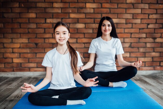 Twee jonge zussen beoefenen yogapositie in een indoor gymstudio. Gezond en wellness-levensstijlconcept