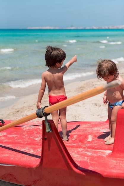 Twee kinderen op het strand staan op peddel boot