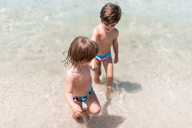 Twee kinderen spelen in water aan de kust