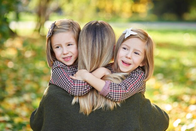 Twee kleine meisjes die hun moeder omhelzen