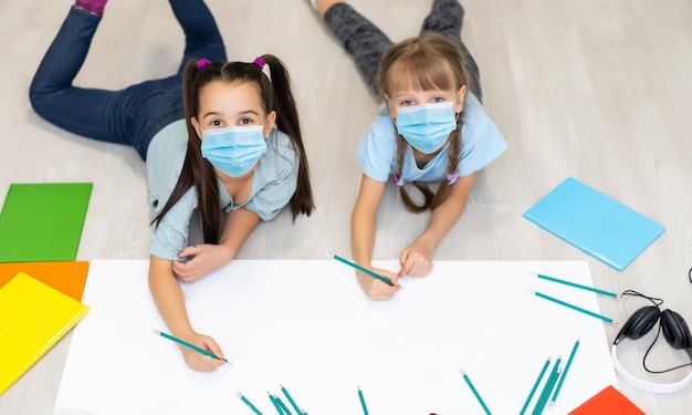 twee kleine meisjes met een waanzinnig masker studeren thuis.