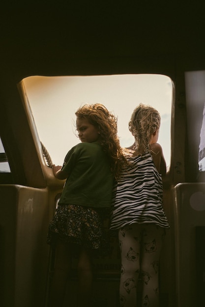 Twee kleine vriendinnen reizen op een boot, kijken uit het open raam. Kinderen op reis.