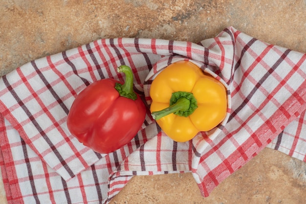 Twee kleurrijke paprika's die op tafellaken liggen