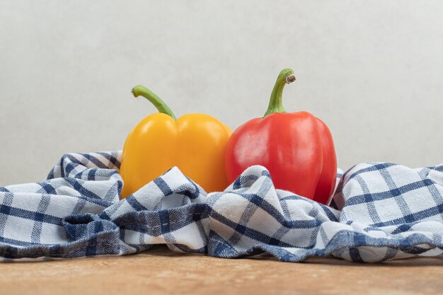 Twee kleurrijke paprika's die op tafellaken liggen