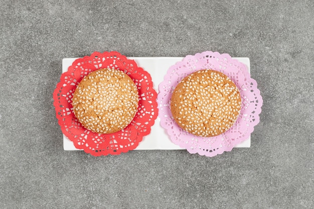 Twee koekjes met sesamzaadjes op witte schotel
