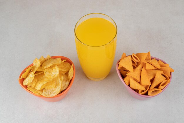 Gratis foto twee kommen chips en een glas sap