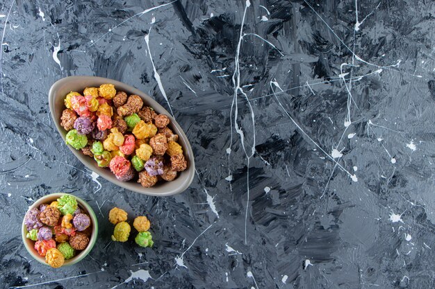 Twee kommen kleurrijke smakelijke popcorns op marmeren oppervlak.