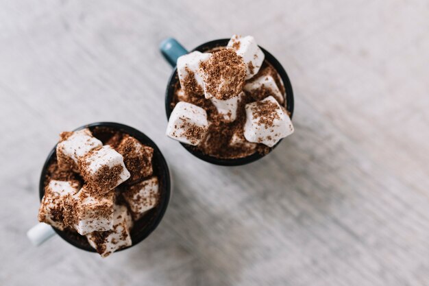 Twee kopjes met marshmallows en cacaopoeder