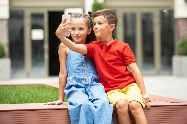 Twee lachende kinderen, jongen en meisje nemen samen selfie in de stad, stad in zomerdag