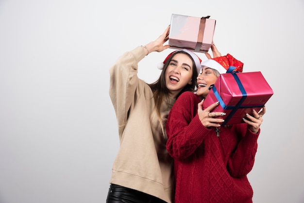 Twee lachende meisjes in kerstmuts met feestelijke kerstcadeautjes.