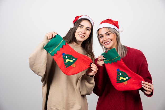 Twee lachende meisjes in kerstmuts met kerstsokken.