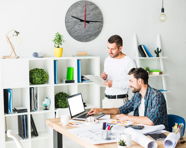 Twee mannelijke collega die in bureau werkt