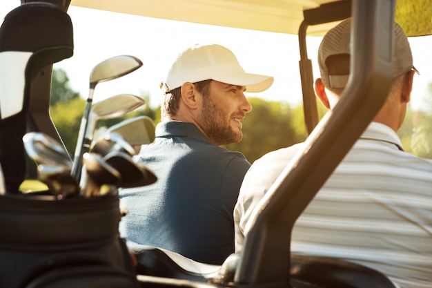 Twee mannelijke golfers zitten in een kar