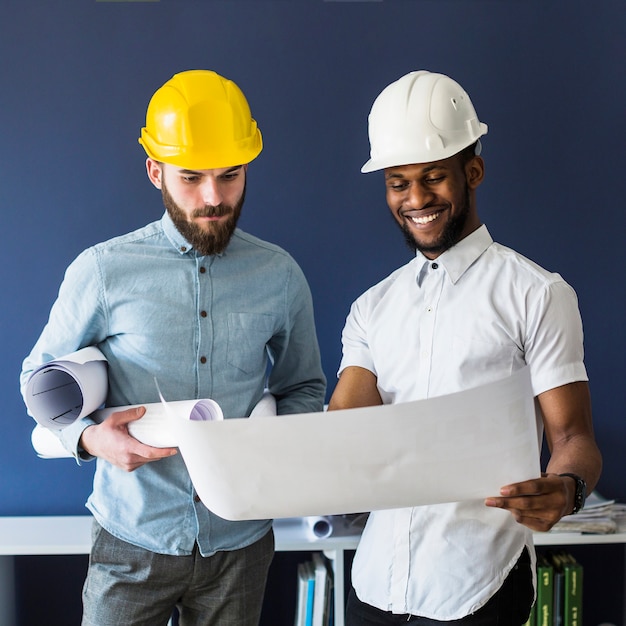 Twee mannelijke ingenieurs die blauwdruk bekijken