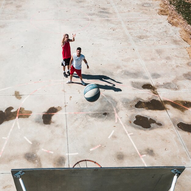 Twee mannelijke spelers die basketbal uitoefenen