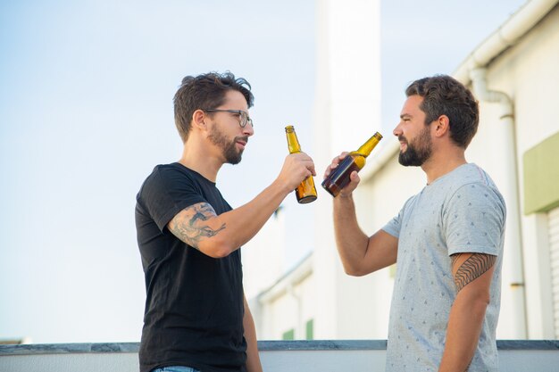 Twee mannelijke vrienden die goed nieuws delen en bier drinken