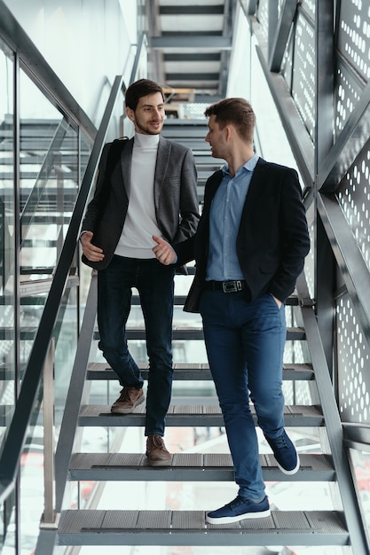 Gratis foto twee mannen gaan naar boven, trappen af terwijl ze kletsen