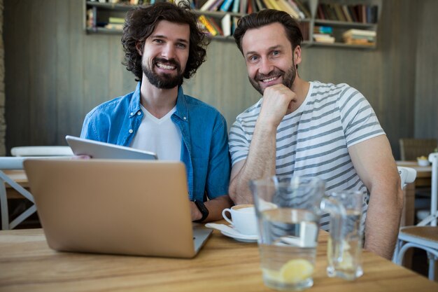 Twee mannen met behulp van digitale tablet en laptop bij coffee shop