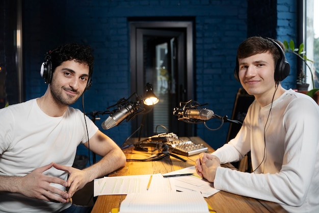 Gratis foto twee mannen met microfoons en koptelefoon die een podcast draaien