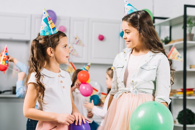 Twee meisjes die elkaar bekijken terwijl het vieren verjaardag in keuken