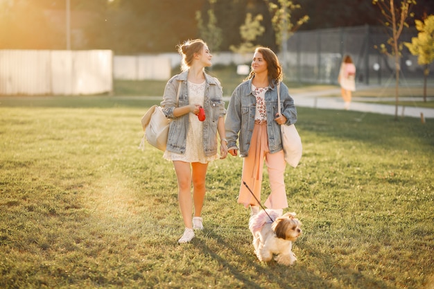 Twee meisjes die in een park met een kleine hond wallking