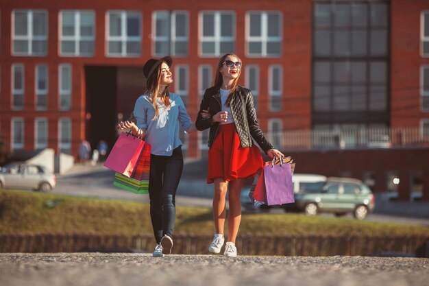 Twee meisjes lopen met boodschappentassen op straten van de stad op zonnige dag
