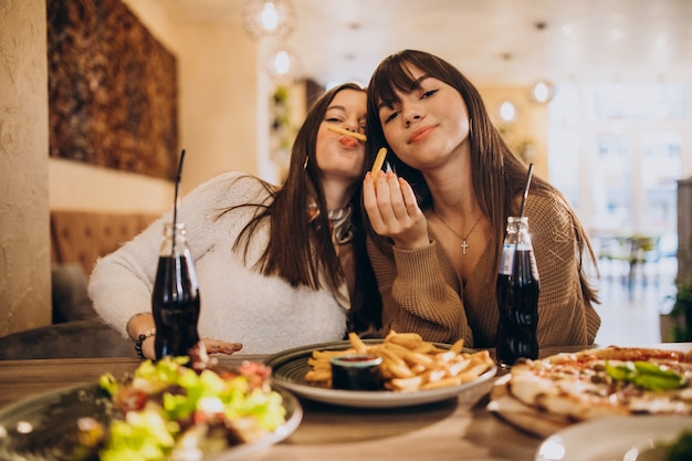 Twee meisjesvrienden die pizza in een koffie eten