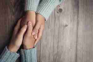 Gratis foto twee mensen hand in hand samen met liefde en warmte op houten tafel