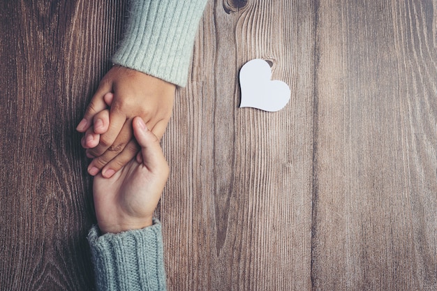 Twee mensen hand in hand samen met liefde en warmte op houten tafel