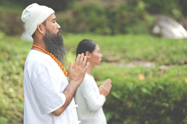 Twee mensen in witte outfit die in de natuur mediteren