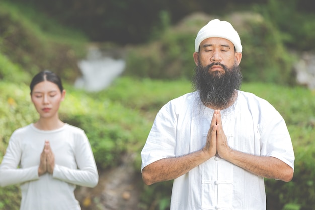 Twee mensen in witte outfit die in de natuur mediteren