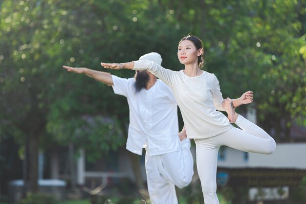 Twee mensen in witte outfit doen yoga in de natuur