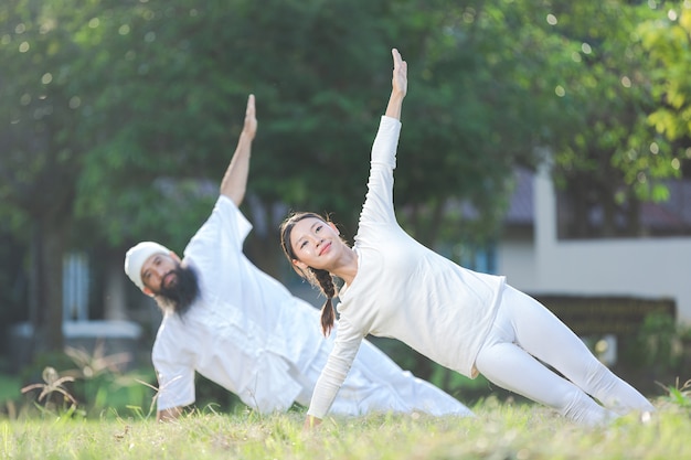 Twee mensen in witte outfit doen yoga in de natuur