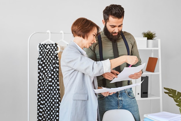 Twee modeontwerpers in atelier die plannen voor kledinglijnen raadplegen