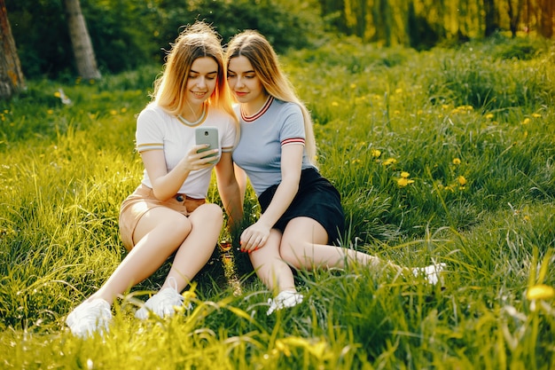 twee mooie jonge mooie meisjes met glanzend blond haar en een rok en zitten met telefoon