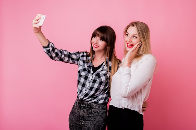 Twee mooie meisjes die zelfportret maken door mobiele telefoon