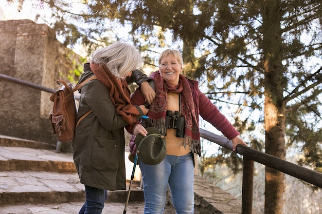 Twee oudere vriendinnen genieten van een wandeling in de natuur terwijl ze een verrekijker gebruiken