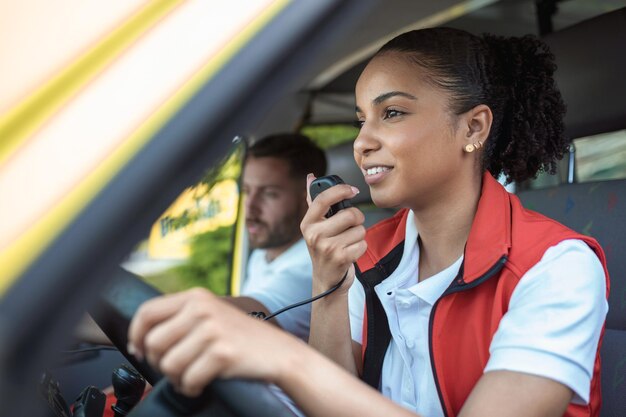 Twee paramedici in de ambulance Afro-Amerikaanse vrouwelijke paramedicus rijden en praten over de radio