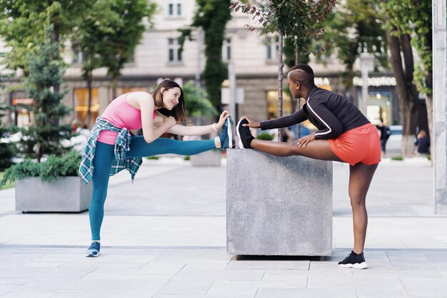 Twee passen diverse jonge vrouwen die samen aan het trainen zijn op het stadsplein en die rekoefeningen en handverlengingen doen