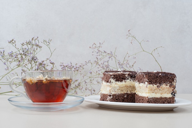 Twee plakjes tiramisu cake en kopje thee op wit oppervlak