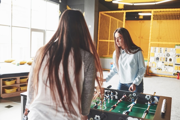 Gratis foto twee prachtige tweelingmeisjes spelen tafelvoetbal en hebben plezier.