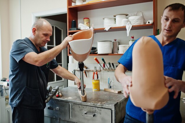 Twee prothetist man arbeiders maken prothetische been tijdens het werken in laboratorium
